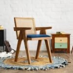 A honey finish solid wood armchair with a hand-woven cane back and a navy blue velvet seat cushion - Modera Furnish.