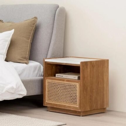 A natural solid wood bedside table featuring a white marble top and a hand-woven cane drawer front - Modera Furnish.