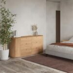 A natural solid wood chest of drawers featuring six storage drawers and architectural curved side panels - Modera Furnish.