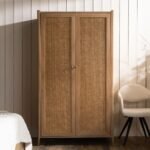 A natural solid wood Bali wardrobe featuring two doors with hand-woven cane inlays and minimalist gold knobs - Modera Furnish.
