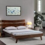 A deep earthy brown solid wood king-size bed featuring an arched headboard with artisanal floral carvings - Modera Furnish.