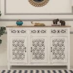 A warm honey sheesham wood sideboard featuring hand-carved geometric floral door panels and three central storage drawers - Modera Furnish.
