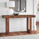 A modern minimalist brown solid wood console table with a thick bridge-style frame base in a bright living room - Modera Furnish