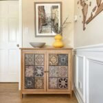 A sophisticated distressed natural finish 2-door accent cabinet featuring twelve unique embossed metal tile inlays and internal storage shelving - Modera Furnish.