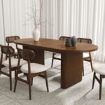 An oval solid wood dining table with ribbed pedestal legs and a natural brown finish - Modera Furnish.