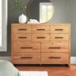 A large natural brown solid wood chest of ten drawers with slim black minimalist handles in a modern bedroom - Modera Furnish