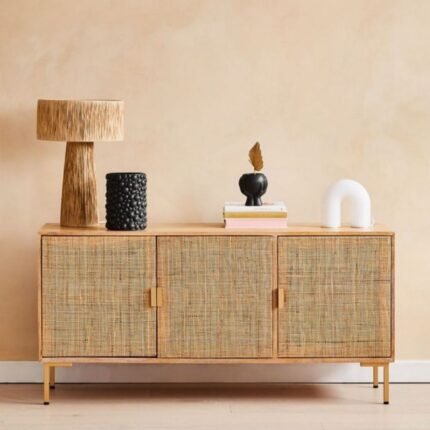 A natural finish solid mango wood sideboard featuring three doors with webbed rattan panels and brass-finished legs - Modera Furnish.