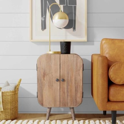 A natural wood side cabinet featuring a rounded barrel silhouette with vertical fluted detailing and splayed legs - Modera Furnish.